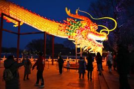 2024年2月9日，农历龙年除夕，人们聚集在北京一个公园观赏巨龙雕像 (AFP)
